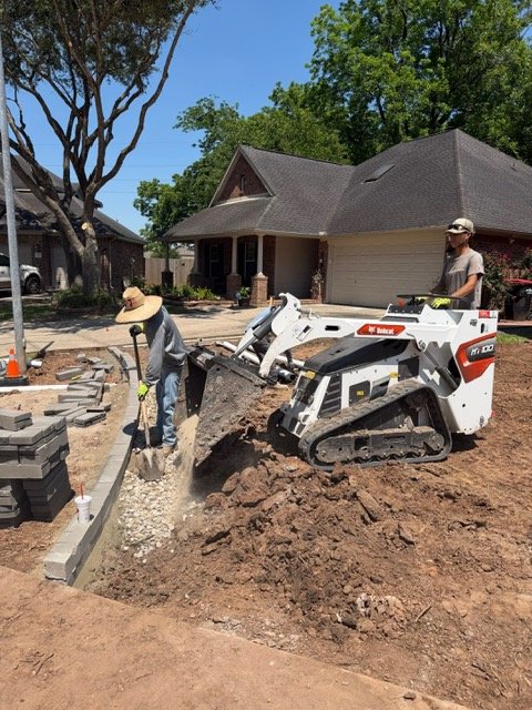 Compact track loader excavating a residential drainage trench