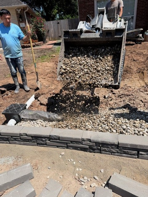 Drainage inlet and stone base beside a retaining wall