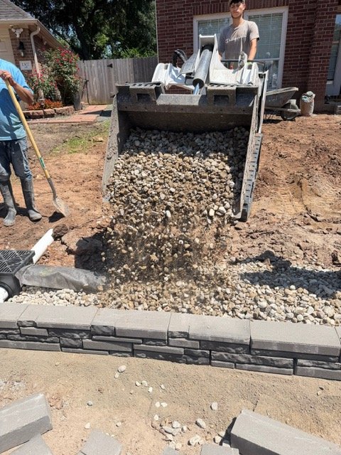 Compact loader placing drainage aggregate on a residential project