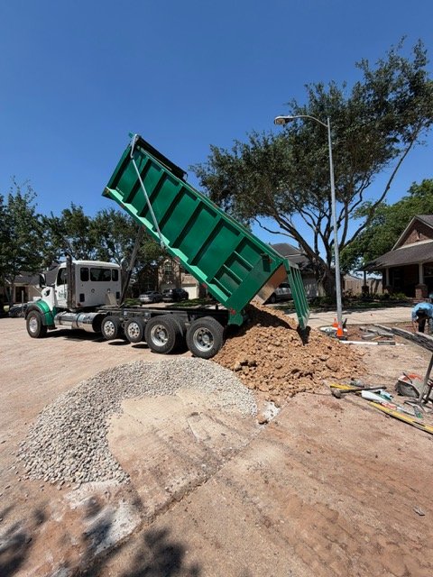 Dump truck delivering bulk material to a residential site